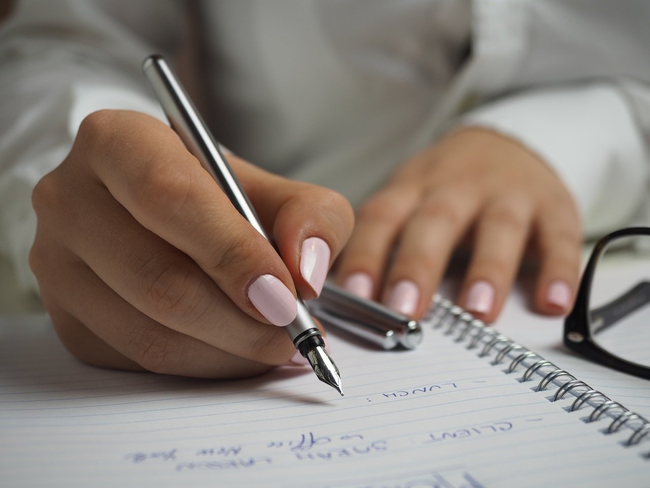 Close up of woman's hands writing in a notebook