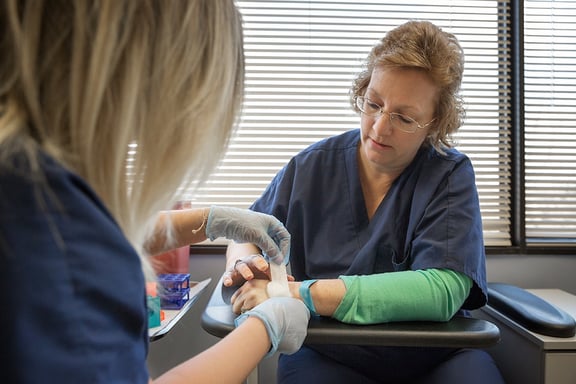 Medical assistant places bandage on woman's hand