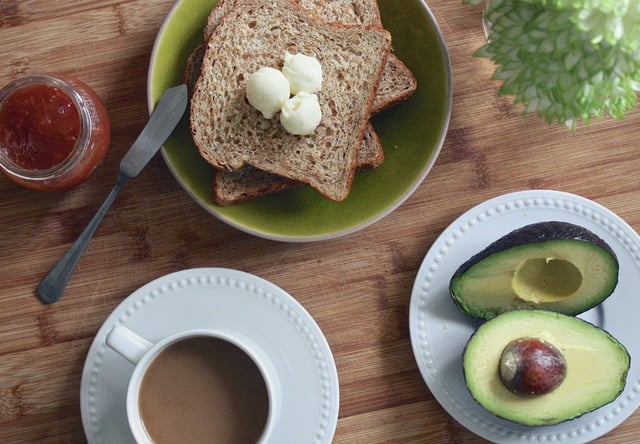 Buttered toast on a plate next to an avocado and jar of salsa