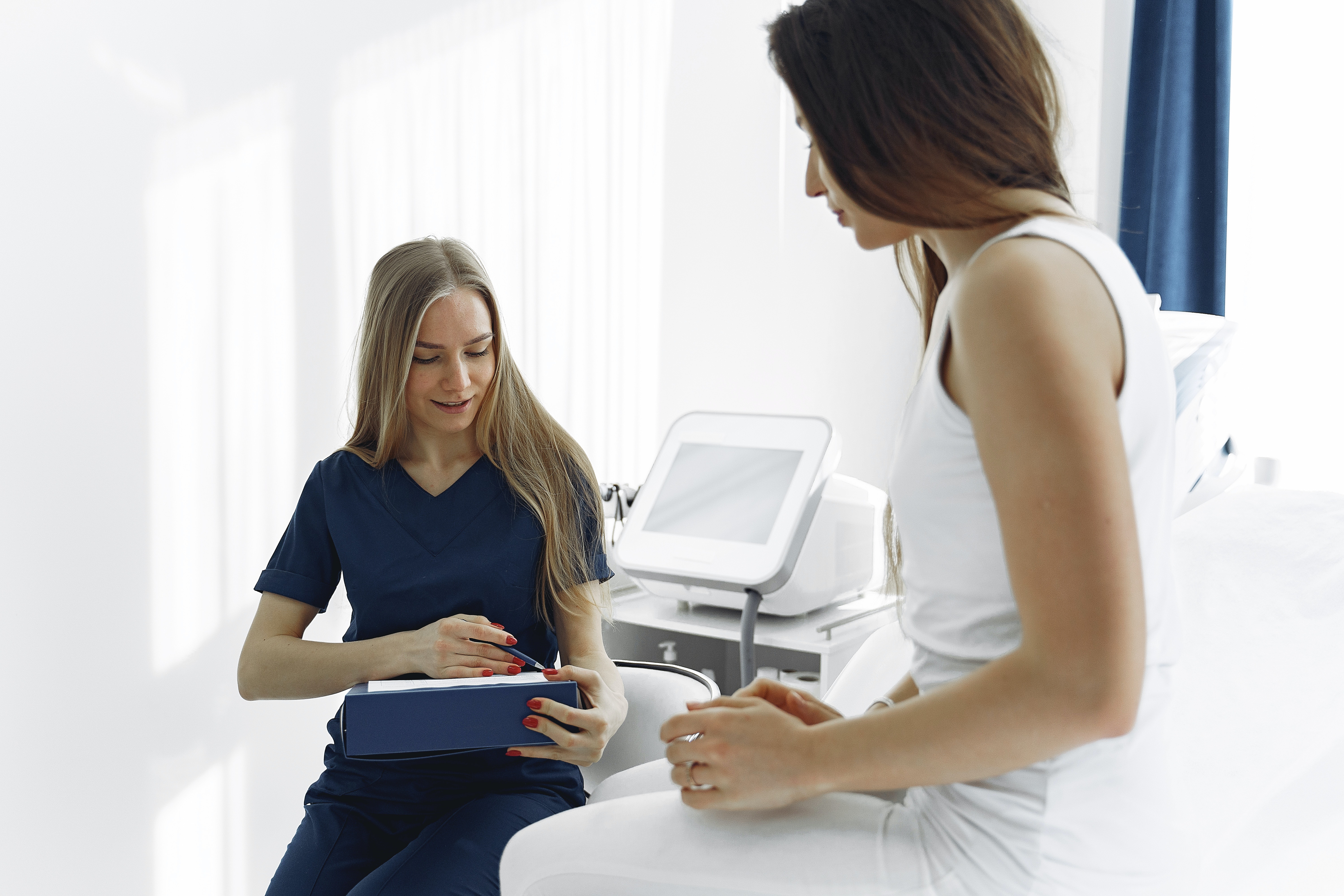 woman-in-blue-scrub-suit-helping-woman-sitting-on-bed-3985299