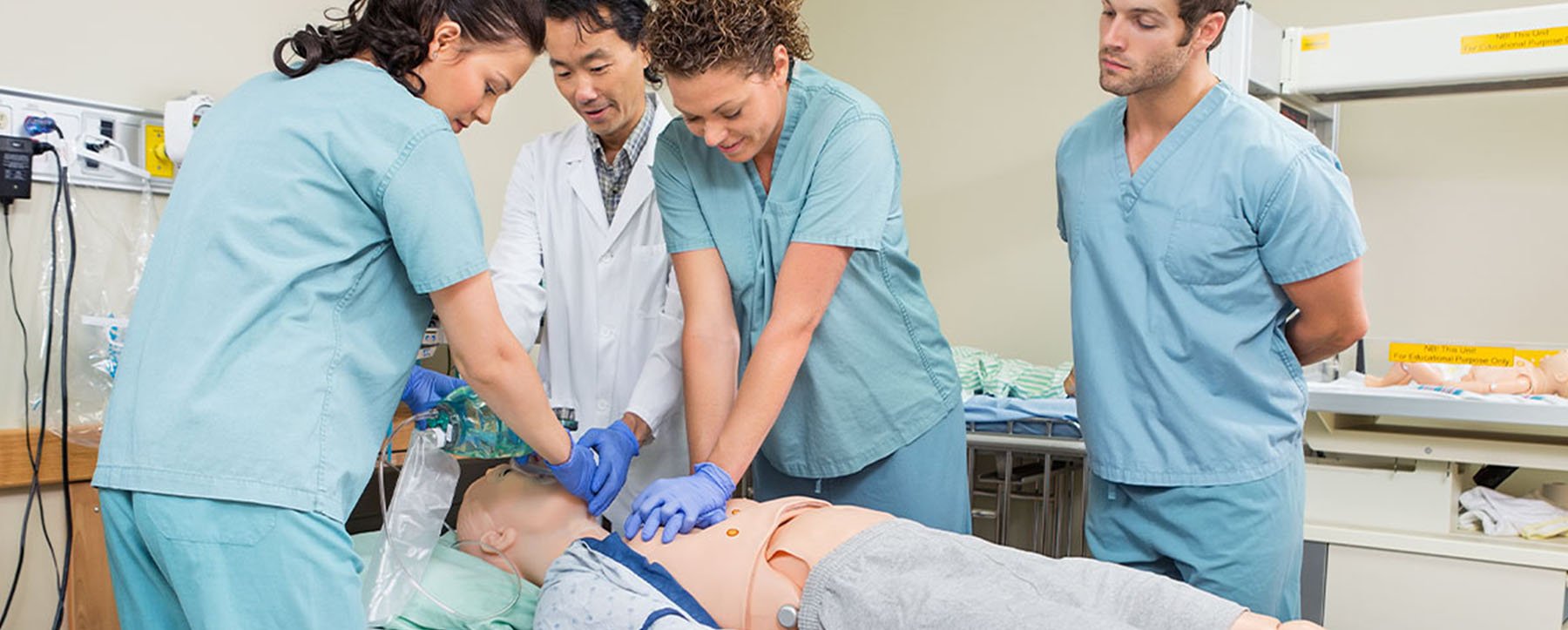 CTE instructor teaches students how to perform CPR on a dummy