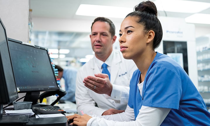 pharmacist-showing-pharmacy-technician-perscriptions-on-the-computer