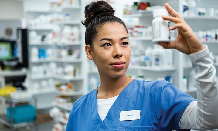 pharmacy-technician-checking-perscription-on-customers-pill-bottle