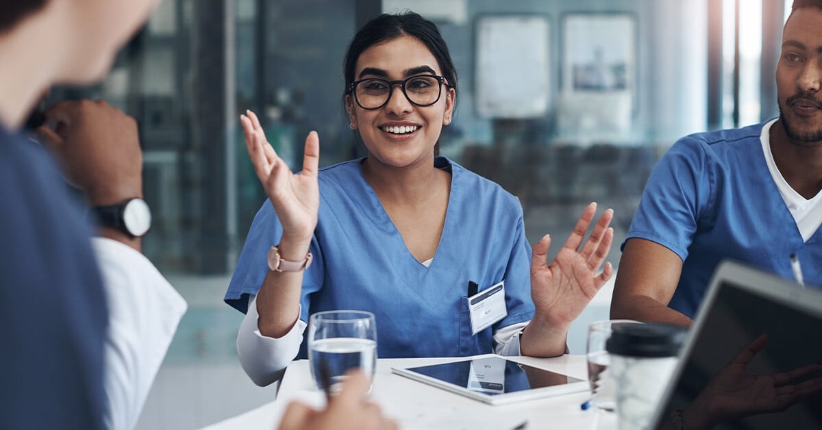 A healthcare professional sits at a table with colleagues