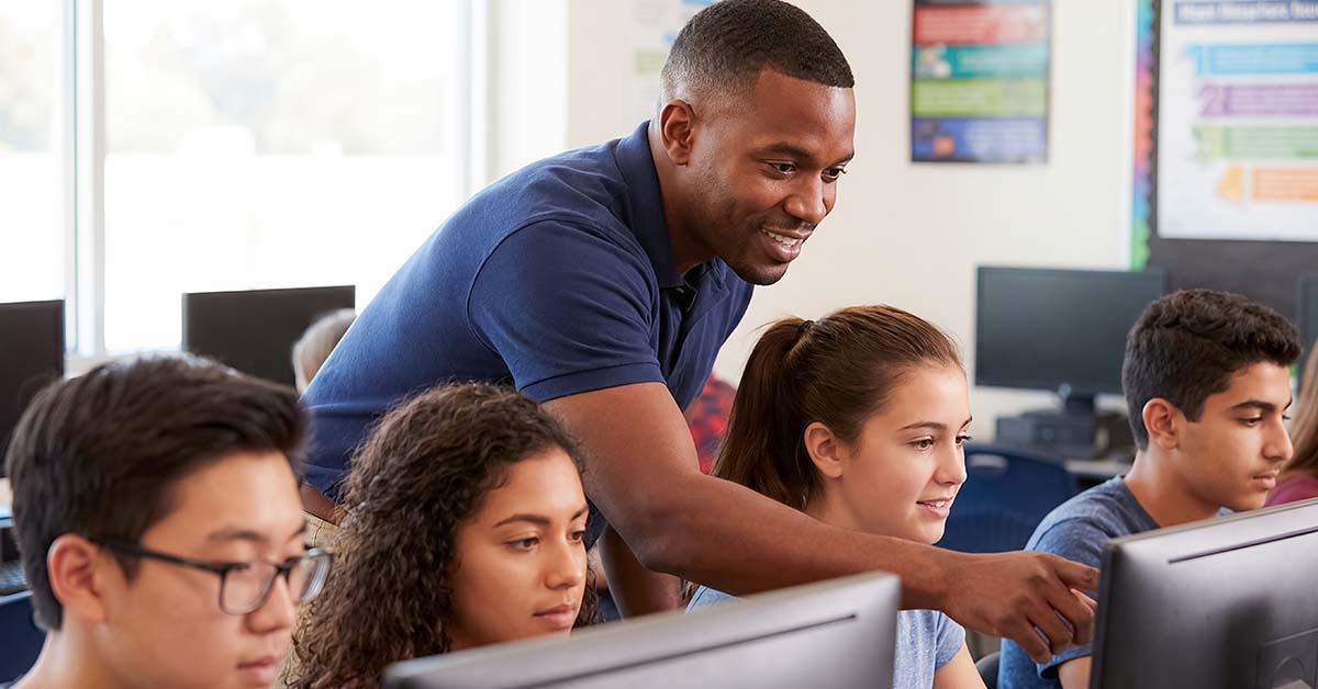 An educator works with students at their computers